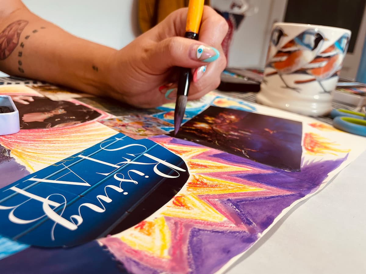 Woman at a table with collage materials in natural light